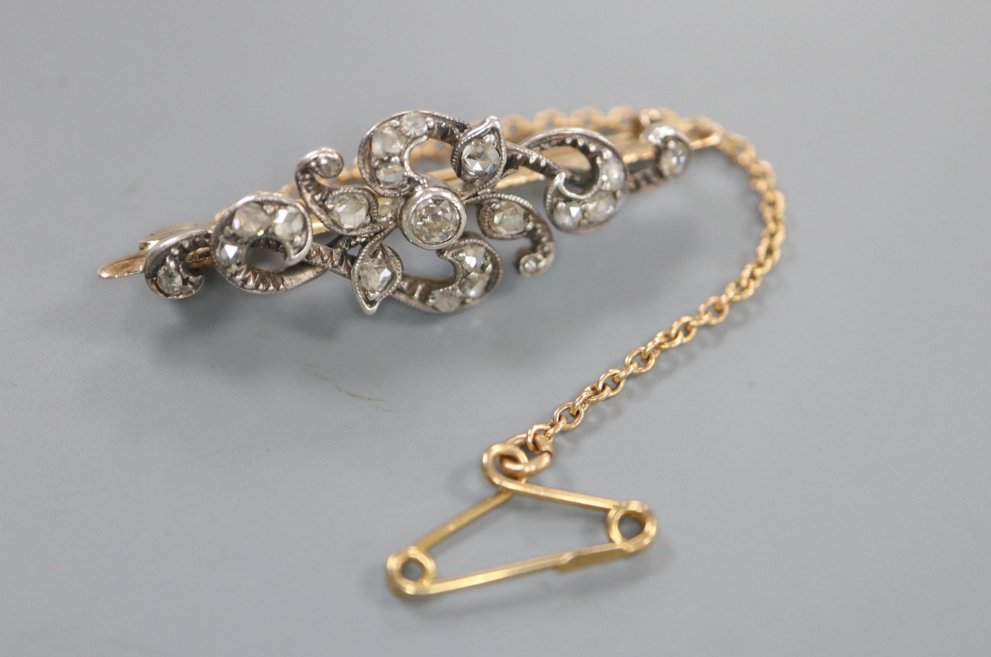 A Victorian yellow and white metal, round and rose cut diamond set scrolling bar brooch, 36mm, gross 3.8 grams.